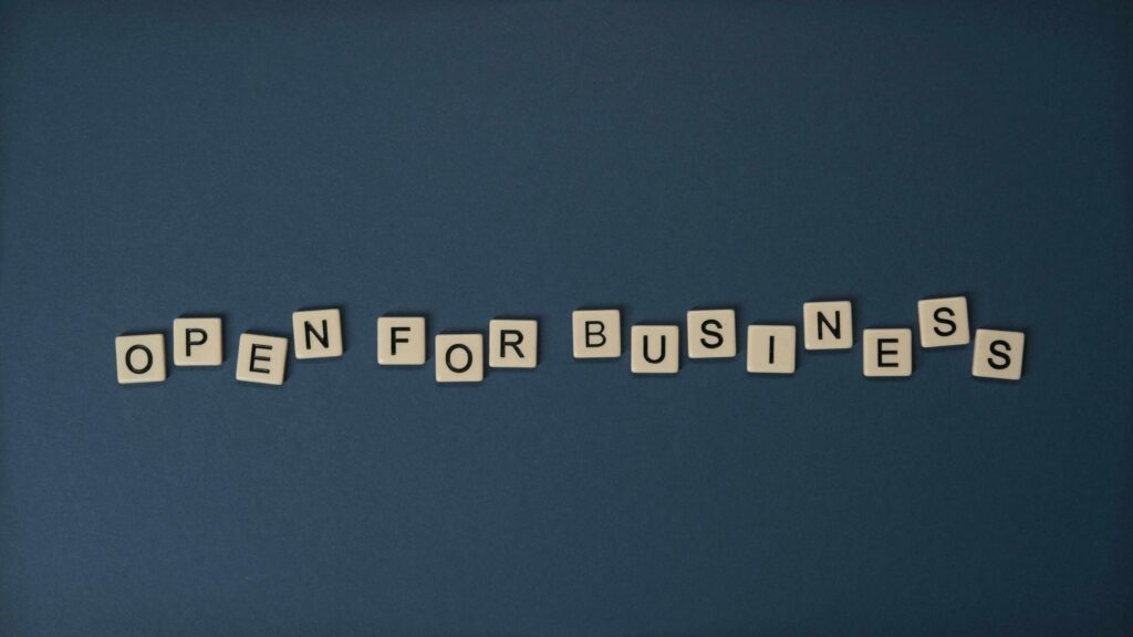 The words open for business spelled out in scrabble tiles